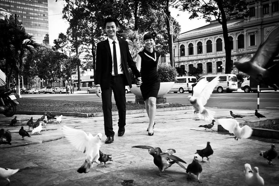couple walk through pigeons