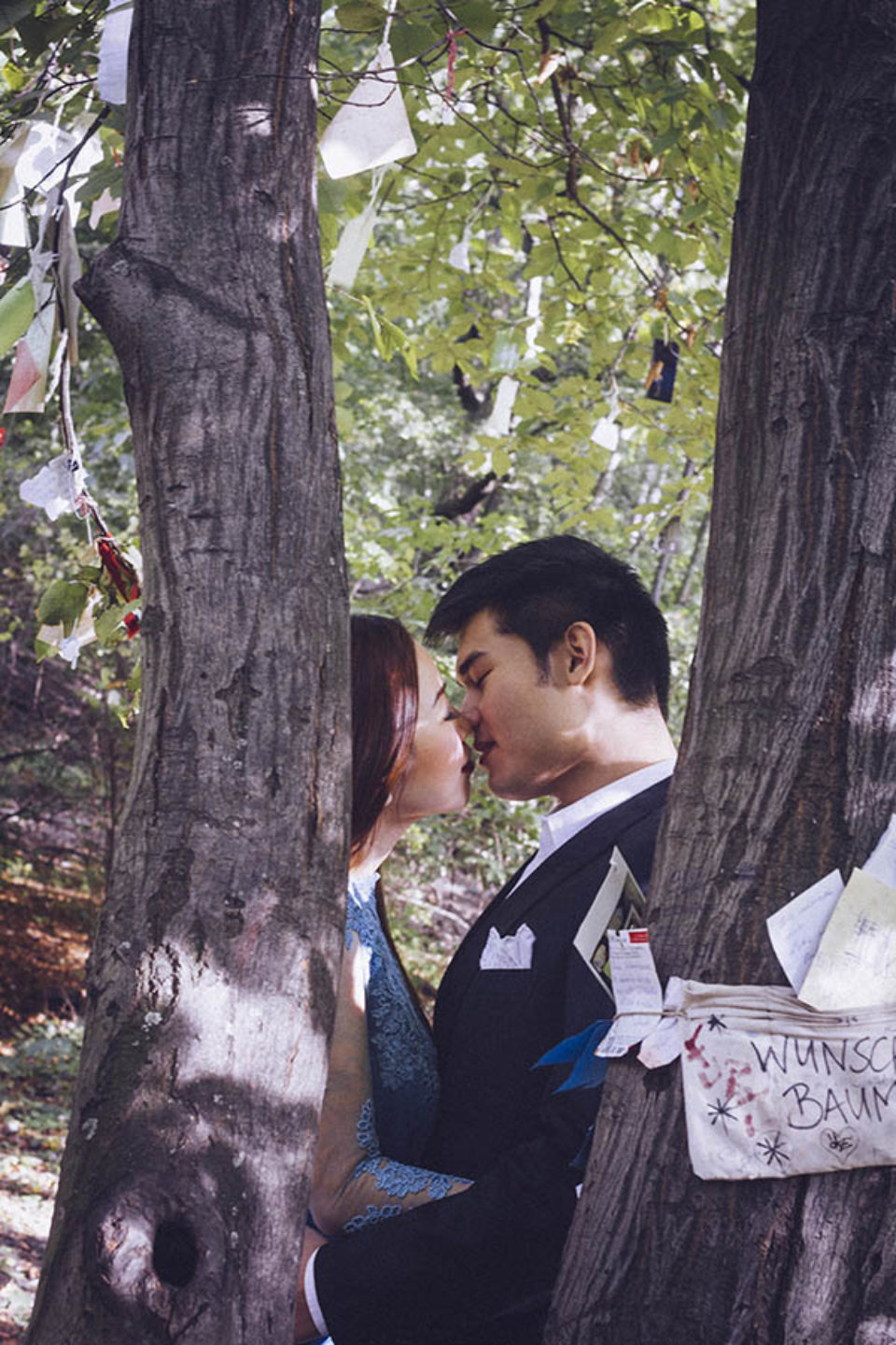 A couple kissing behind a tree