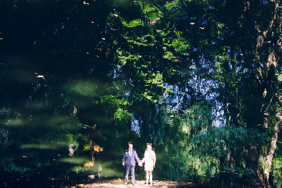 Reflection in pond of couple holding hands