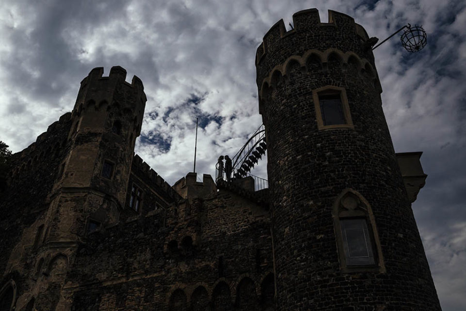 Bride and groom silhouetted at a castle