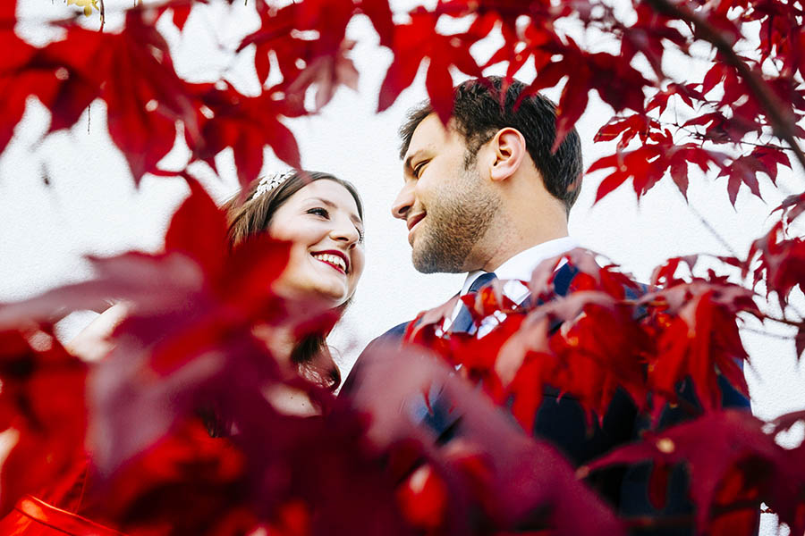 Couple portrait through red maple leaves
