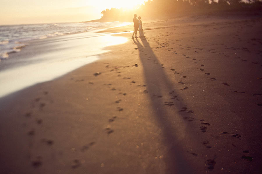 Destination wedding photographer - Long shadows of newlyweds on beach