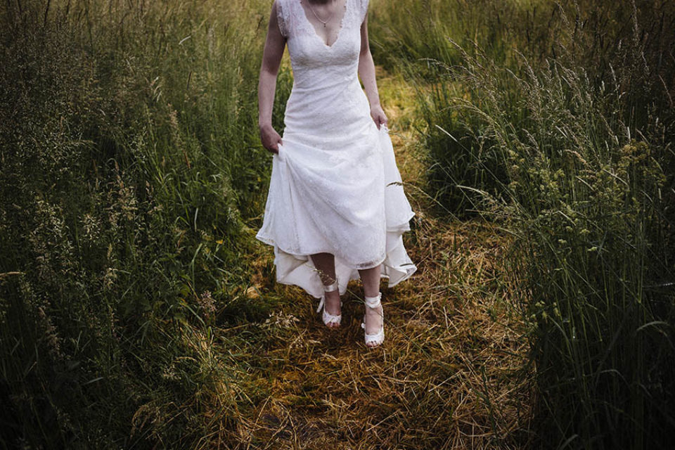 Bride walking through a field of grass