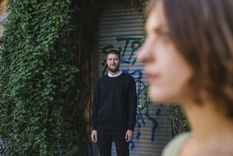 Husband leafy doorway looks at bride