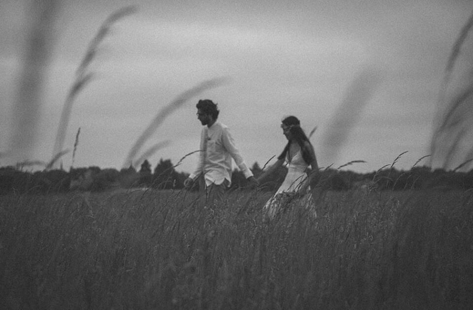 Couple walk through long grass