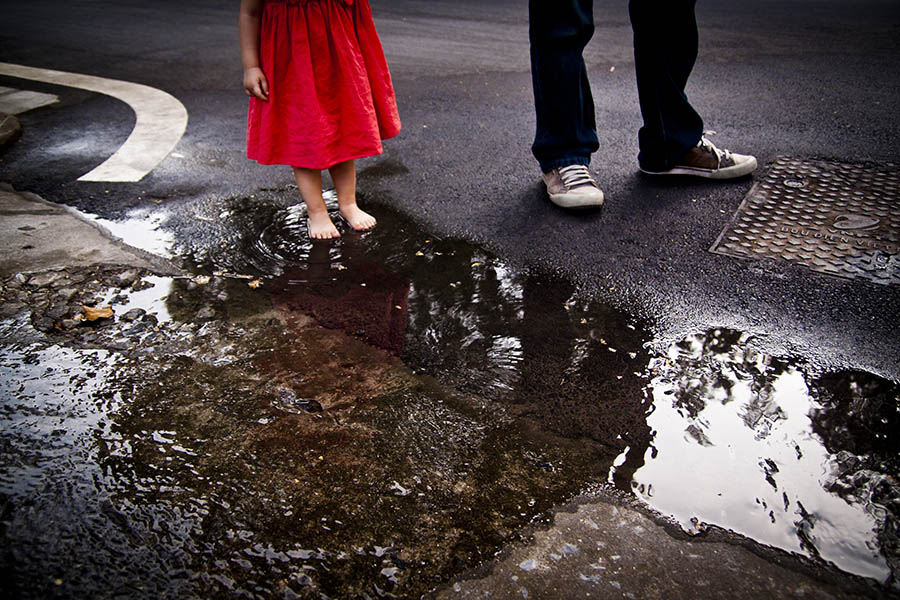 Father and barefooted daughter by puddle