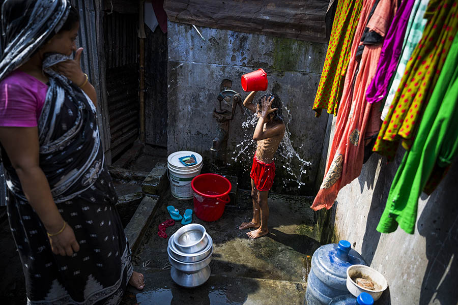 Young girl washes herself in the Korail Slum